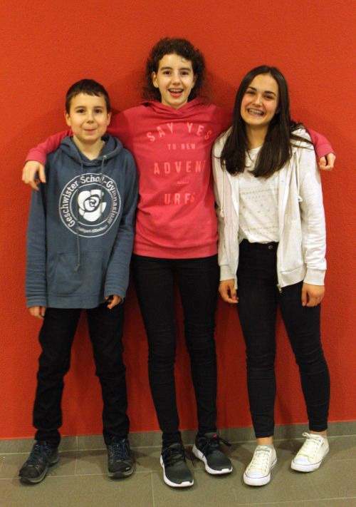 Linus, Leoni und Anna posieren vor einer roten Wand